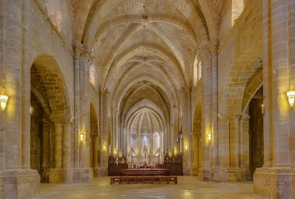 Nave central de la iglesia del monasterio de La Oliva, con bóvedas de piedra y arcos apuntados hasta el ábside iluminado