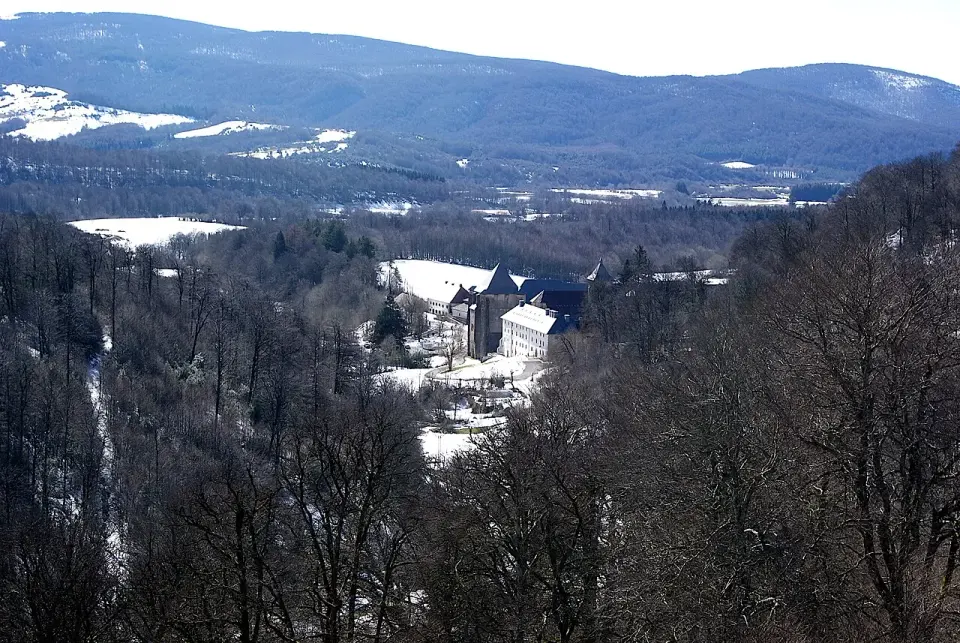 Colegiata de Roncesvalles entre bosques de hayas con restos de nieve, vista desde el alto de Ibañeta