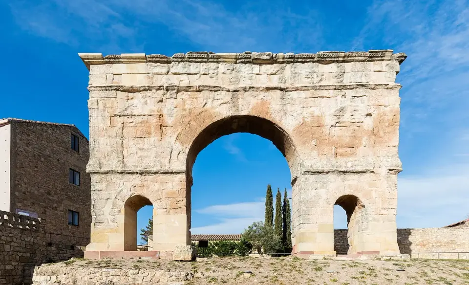 Arco romano de Medinaceli, con un gran vano central y dos laterales más pequeños, bajo un cielo azul