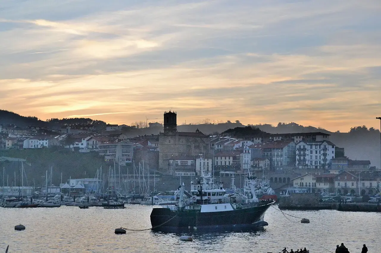 Puerto de Getaria al atardecer, con barcos de pesca amarrados y el casco antiguo y su iglesia detrás