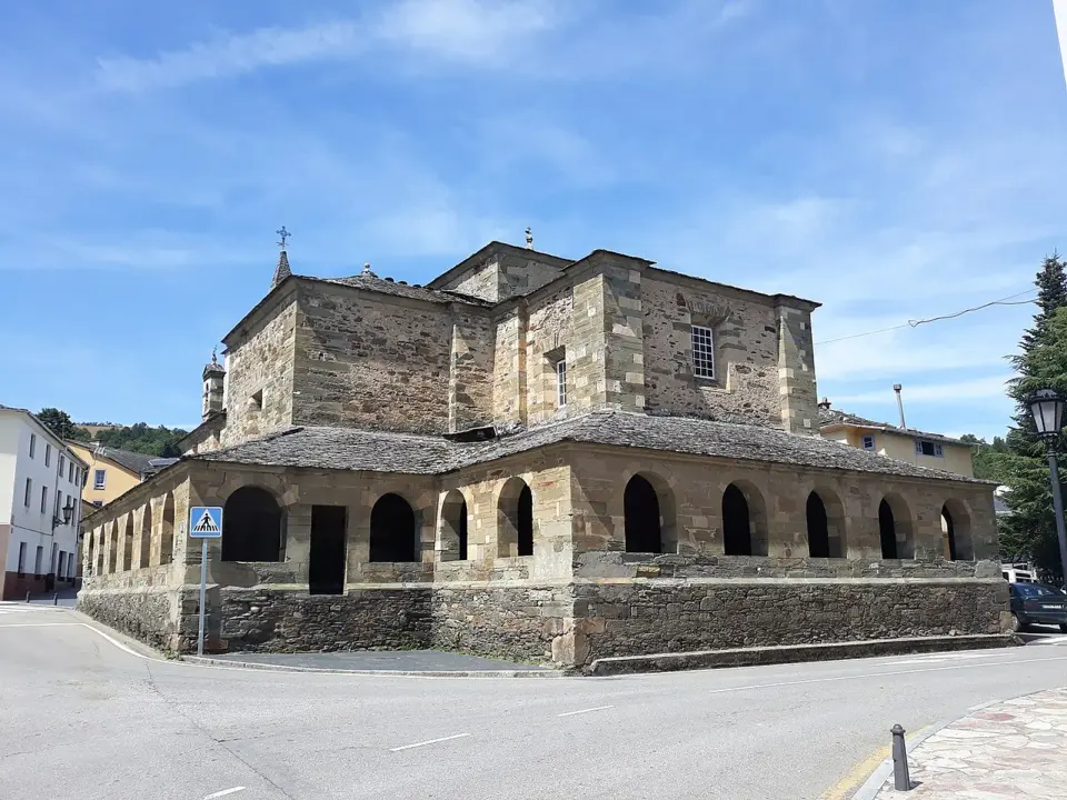 Colegiata de El Salvador en Grandas de Salime, de piedra y tejado de pizarra, con su pórtico de arcos alrededor