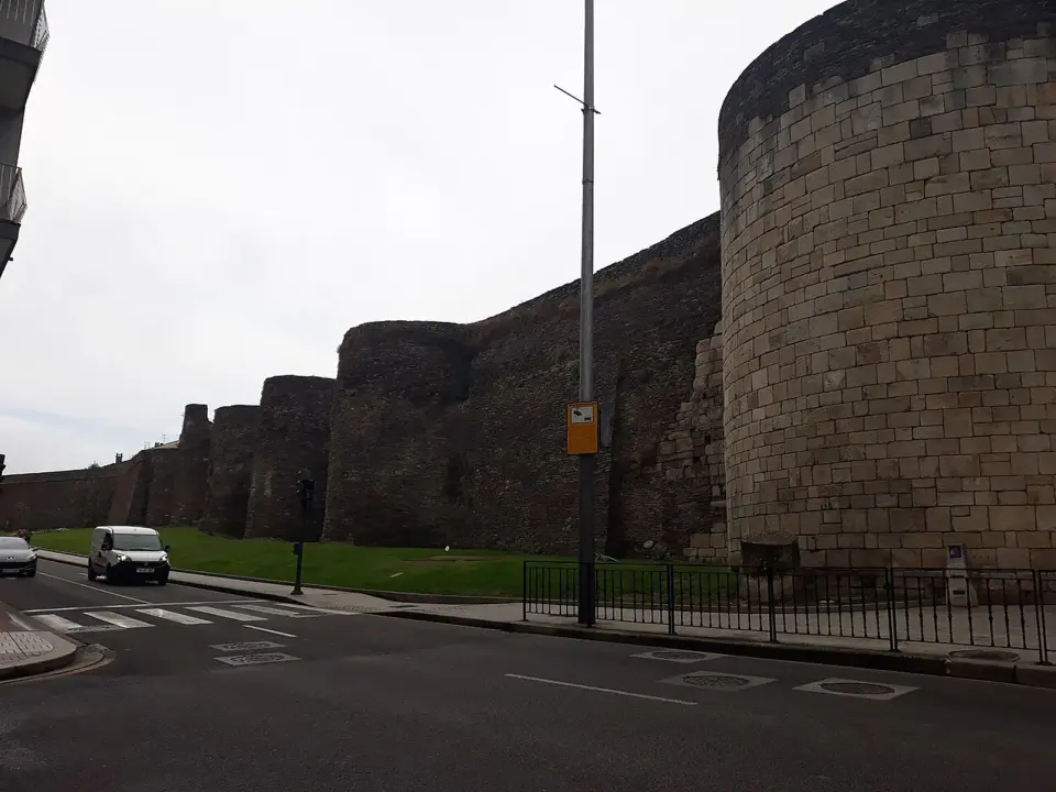 Lienzo y cubos circulares de piedra de la muralla romana de Lugo junto a una calle de la ciudad