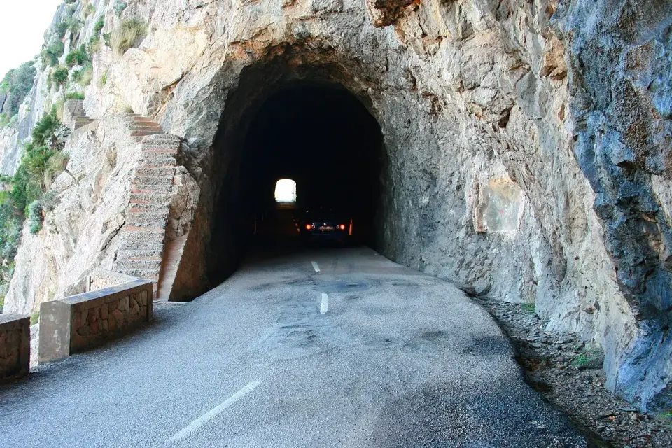 Boca de un túnel estrecho excavado en la roca en la carretera MA-2210, cerca de Cala Figuera