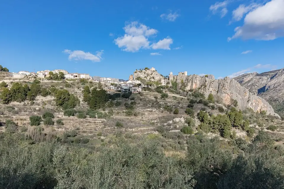 El Castell de Guadalest sobre una cresta de roca caliza, con bancales de olivos en primer plano