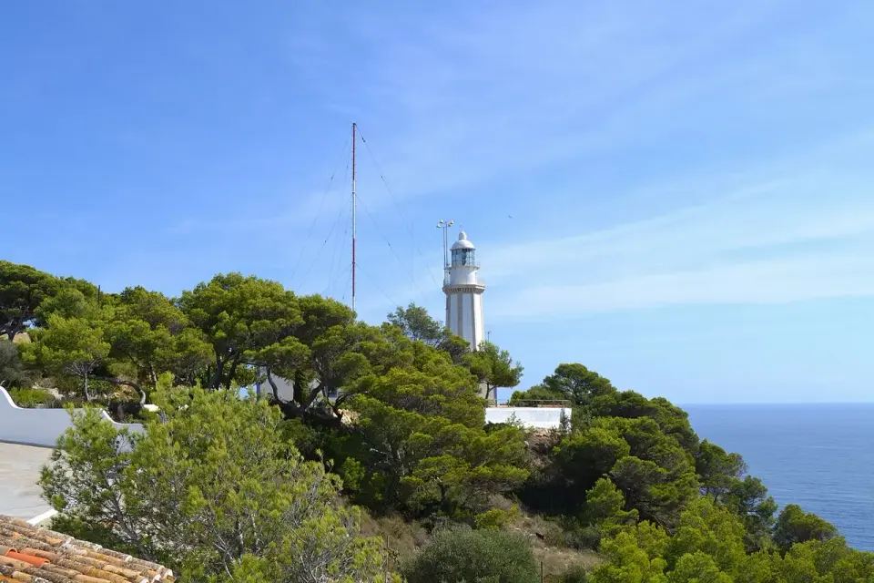 Faro del cabo de la Nao entre pinos, sobre el mar Mediterráneo