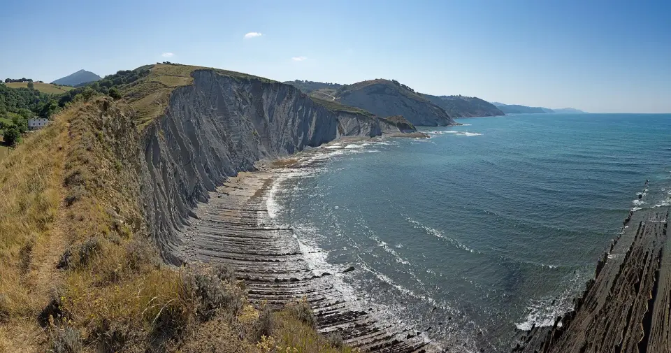 Acantilados de flysch con estratos de roca inclinados que entran en el mar entre Deba y Zumaia