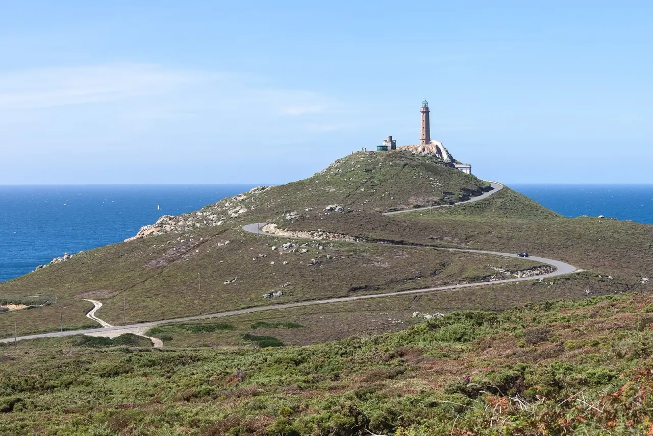 Carretera que sube entre brezos hasta el faro de Cabo Vilán, sobre un promontorio rocoso junto al océano Atlántico