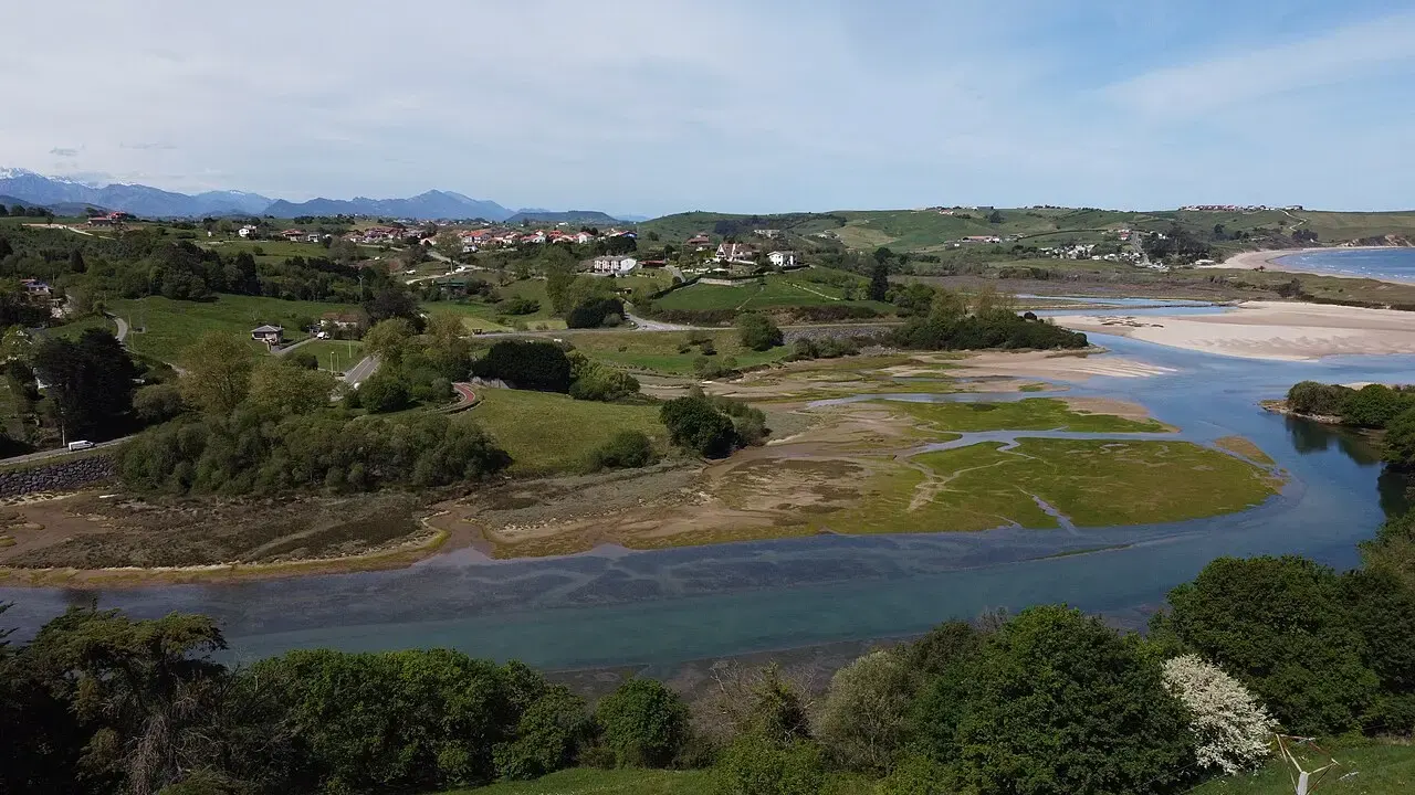 Ría de la Rabia en Comillas con marismas, prados verdes y montañas al fondo