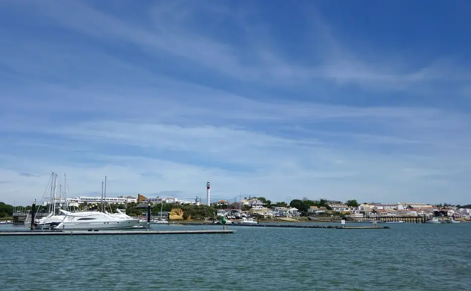 Puerto deportivo de El Rompido con barcos amarrados y el faro al fondo, junto al río Piedras