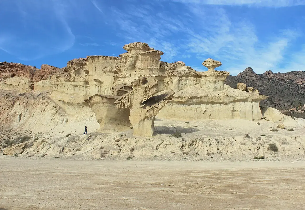 Formaciones de arenisca erosionadas por el viento en forma de setas en las Gredas de Bolnuevo, con una persona al pie para dar escala