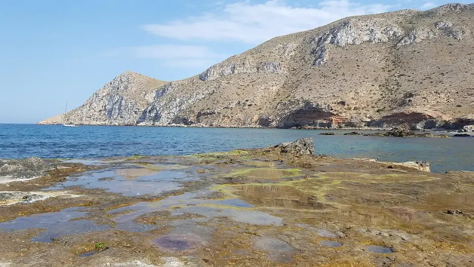 El cabo Cope, montaña árida que cae al mar, visto desde la orilla rocosa de la playa de Cope