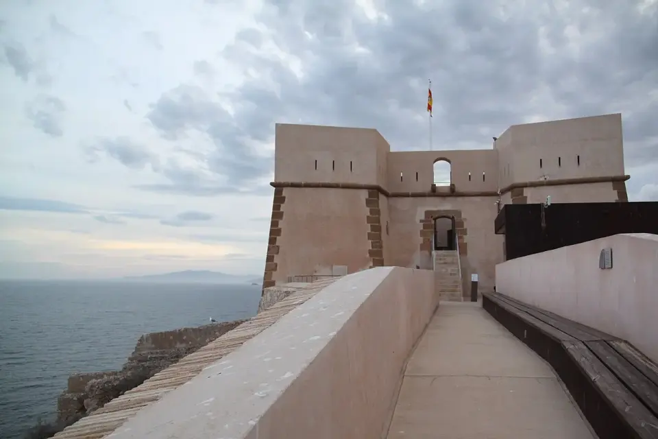 Camino de ronda del castillo de San Juan de las Águilas con su torre y el mar al fondo al atardecer