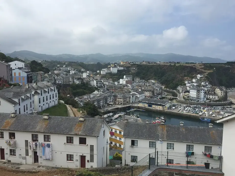 Vista de Luarca con su puerto y las casas blancas alrededor de la bahía bajo un cielo nublado