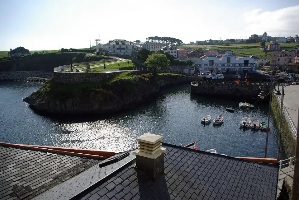 Puerto de Vega con su dársena, barcas amarradas y casas sobre el promontorio