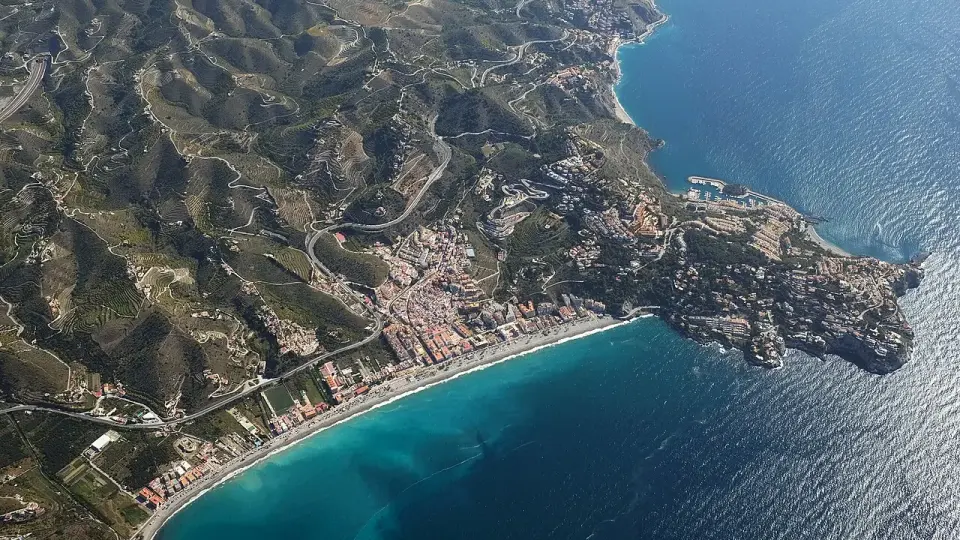 Vista aérea de la bahía de La Herradura, con el pueblo al fondo del valle y la punta de la Mona