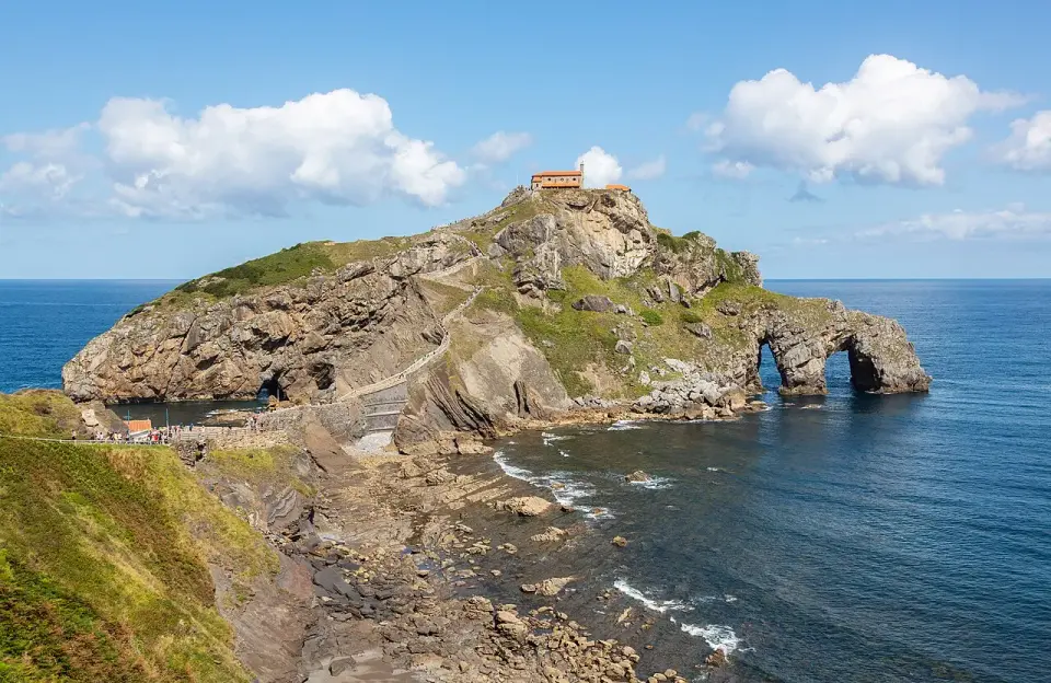 Islote de San Juan de Gaztelugatxe con la ermita en lo alto, el puente de piedra y el camino de escaleras sobre el mar