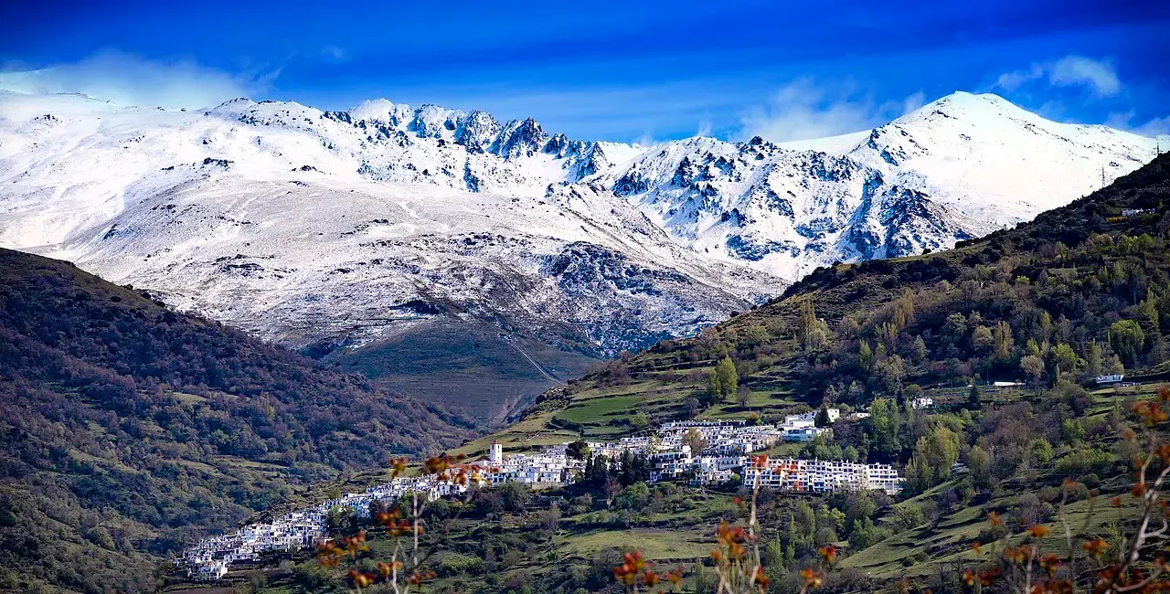 Capileira, con sus casas blancas escalonadas sobre bancales, a los pies de las cumbres nevadas de Sierra Nevada