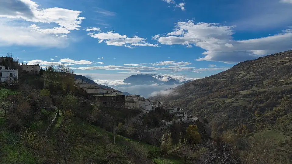 Vista del Barranco de Poqueira desde Capileira, con laderas de monte bajo y nubes sobre las sierras del fondo