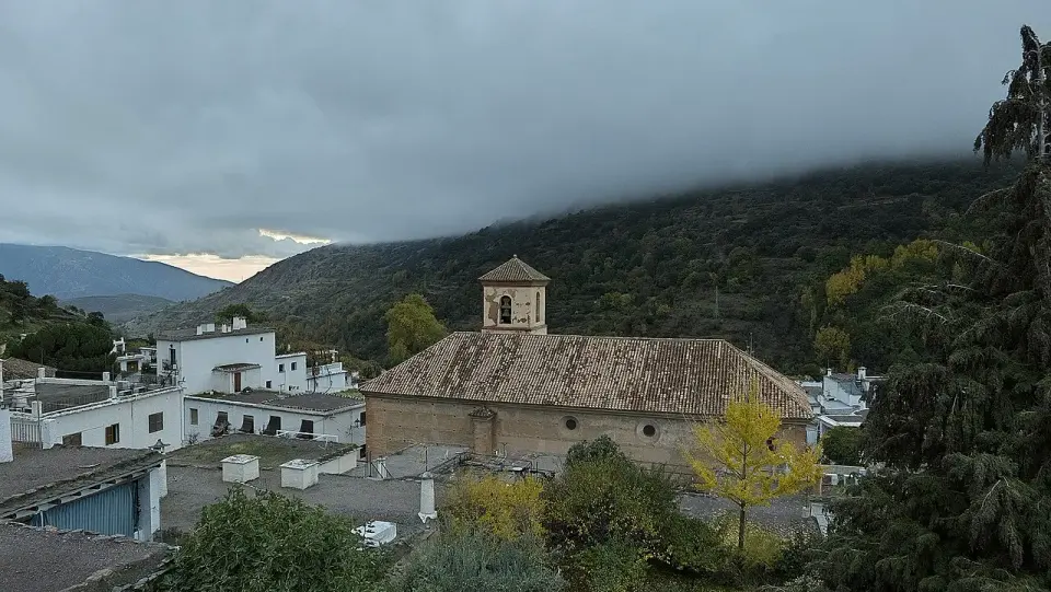 Pampaneira con la iglesia de Santa Cruz entre casas encaladas de tejados planos y la sierra cubierta de nubes