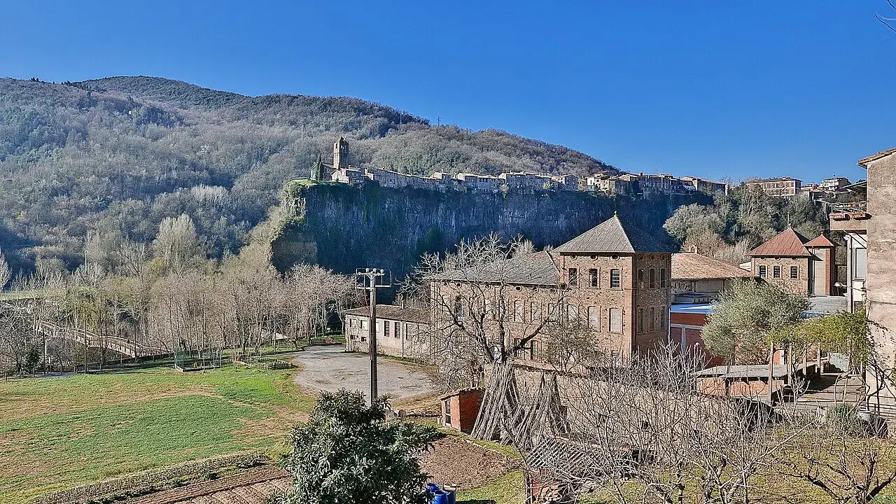 Castellfollit de la Roca alineado sobre un risco de basalto, con casas antiguas y huertas en primer plano
