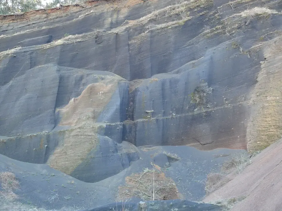 Corte en la ladera del volcán Croscat que deja a la vista las capas de greda volcánica oscura