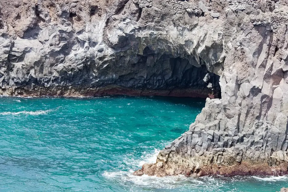 Cueva de lava en los acantilados de Los Hervideros con el mar turquesa entrando en ella