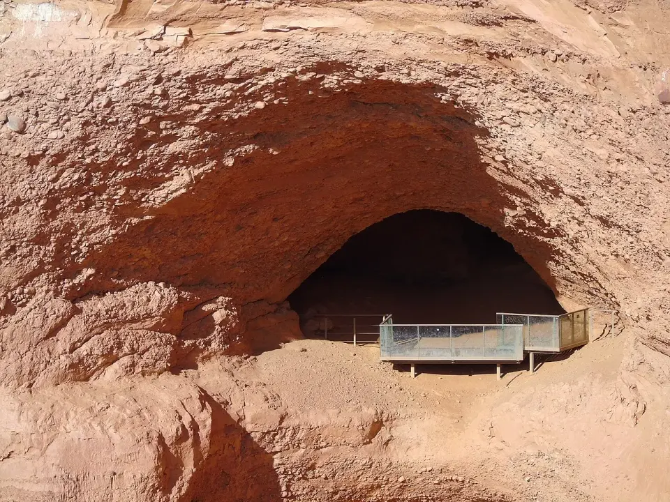 Gran oquedad excavada en la arcilla roja de Las Médulas con una pasarela metálica para los visitantes