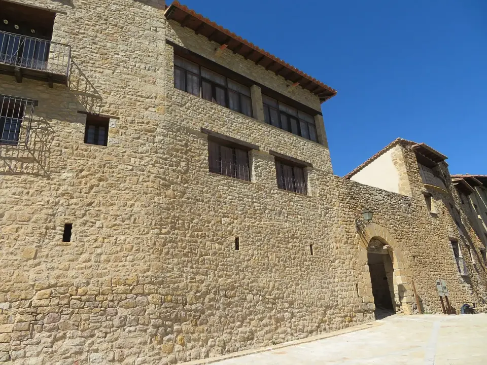 Lienzo de muralla de piedra de Mirambel con casas adosadas y un portal de arco de medio punto