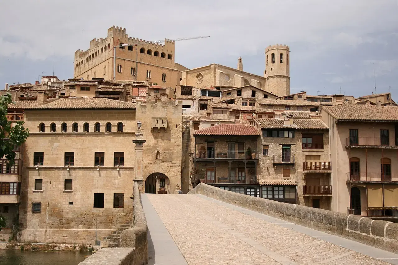 Puente gótico de piedra sobre el río Matarraña en Valderrobres, con las casas del casco antiguo, la iglesia y el castillo en lo alto