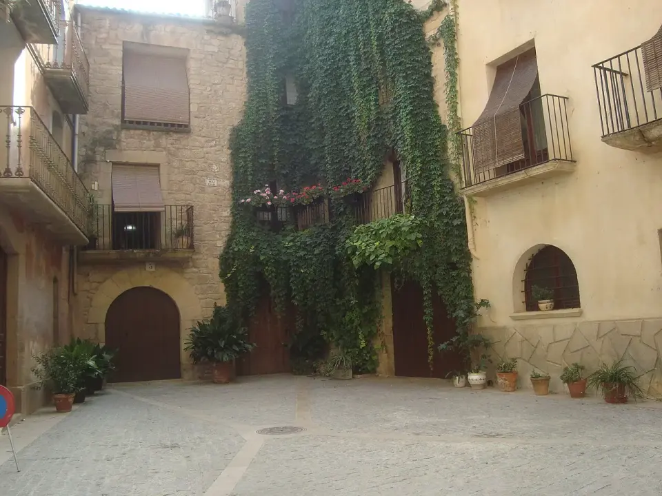 Rincón empedrado de Calaceite con casas de piedra de sillería, balcones de forja y una fachada cubierta de hiedra
