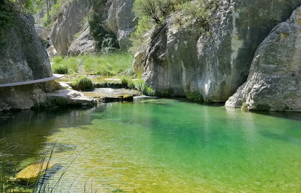 Poza de agua verde turquesa del río Matarraña entre grandes rocas calizas en el Parrizal de Beceite