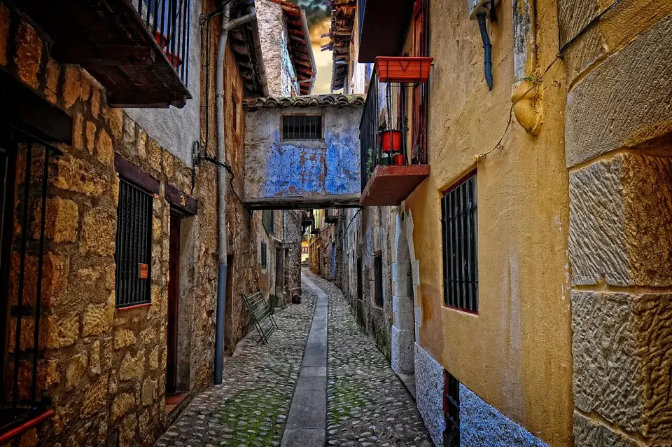 Calle estrecha y empedrada de Valderrobres entre casas de piedra con balcones de madera y un pasadizo al fondo