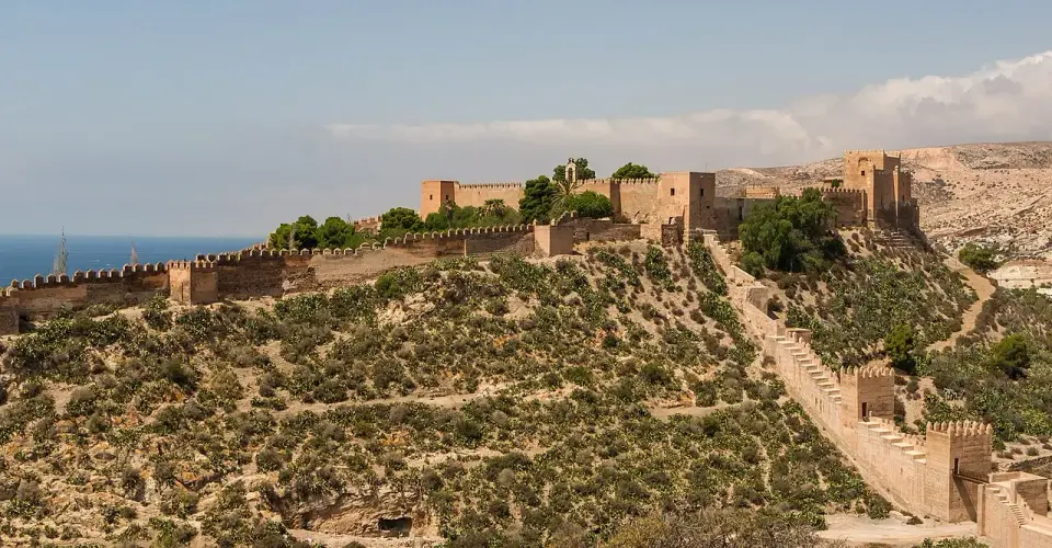 Murallas y torres de la Alcazaba de Almería subiendo por el cerro, con el mar a la izquierda
