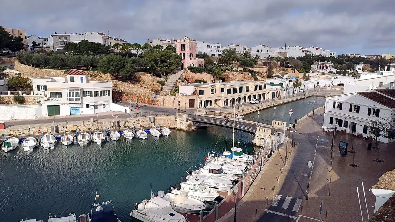 Puerto de Ciutadella con barcas amarradas y casas blancas a ambos lados de la cala