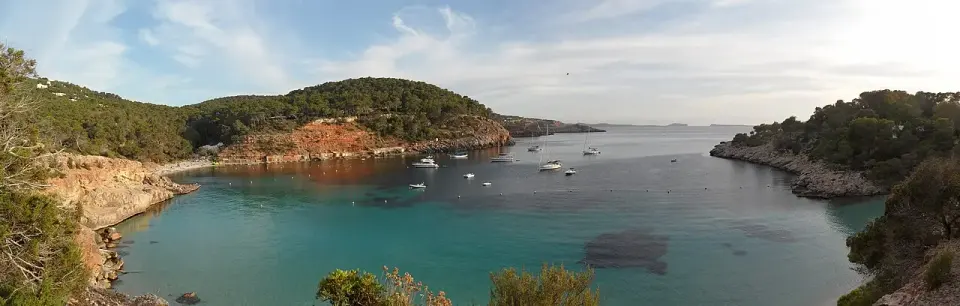 Panorámica de Cala Salada, con agua turquesa y barcas fondeadas entre pinares