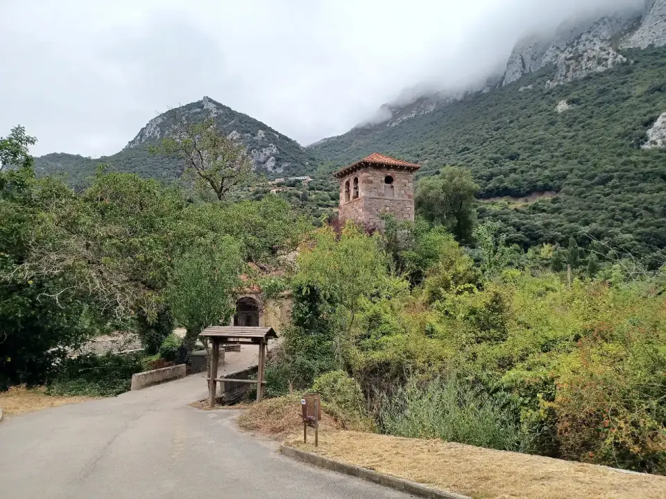 Iglesia prerrománica de Santa María de Lebeña con su torre, rodeada de vegetación y montañas
