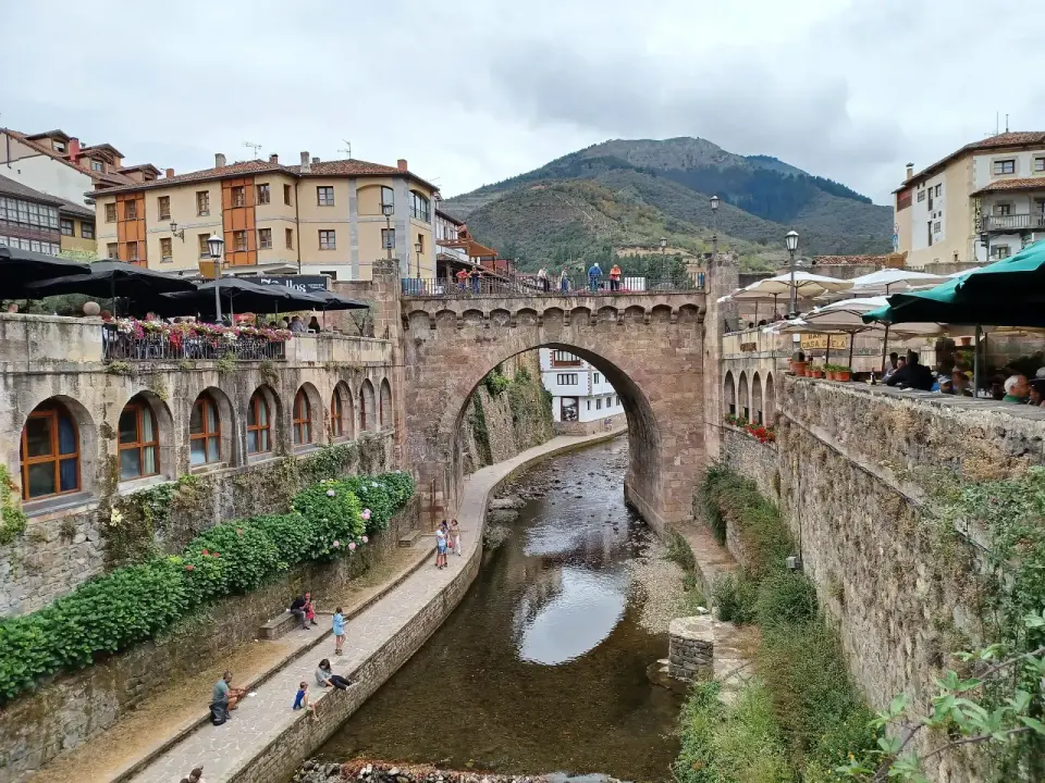 Puente de piedra sobre el río en el centro de Potes, con casas y terrazas a ambos lados