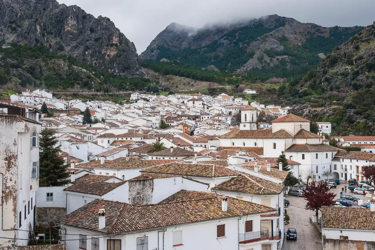 Casas blancas y tejados de Grazalema al pie de las montañas calizas de la sierra, con nubes sobre las cumbres