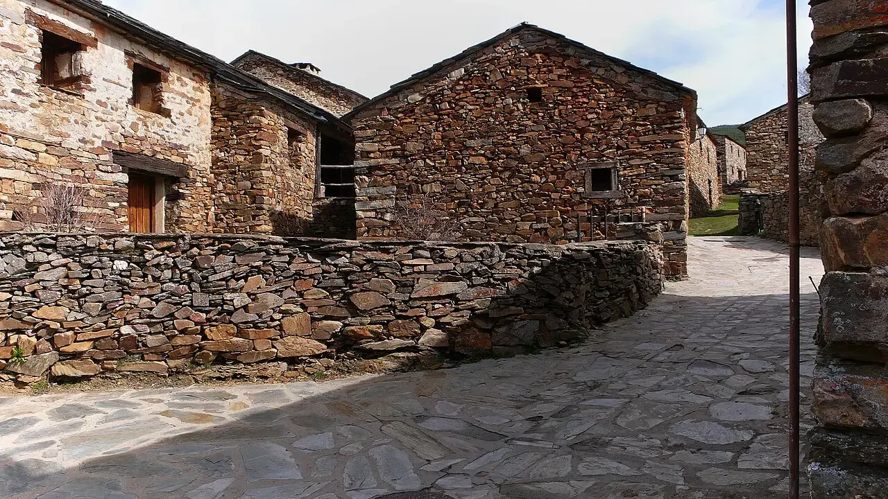 Casas de muros y tejados de pizarra oscura junto a una calle empedrada en Valverde de los Arroyos