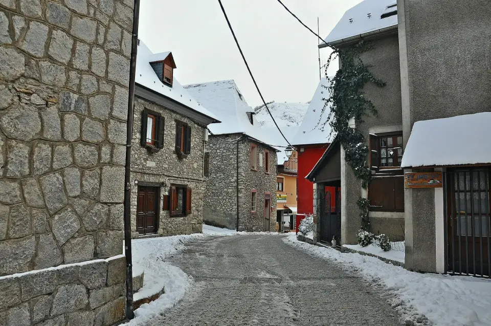 Calle del núcleo antiguo de Salardú con casas de piedra y nieve en el suelo