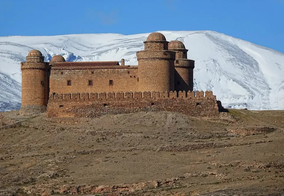 Castillo renacentista de La Calahorra, con cuatro torres cilíndricas, delante de la cara norte nevada de Sierra Nevada