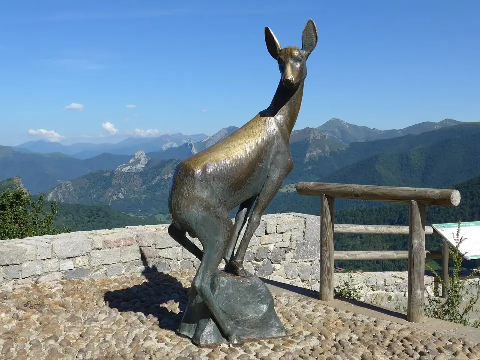 Escultura metálica de un corzo en el mirador del puerto de San Glorio, con montañas al fondo