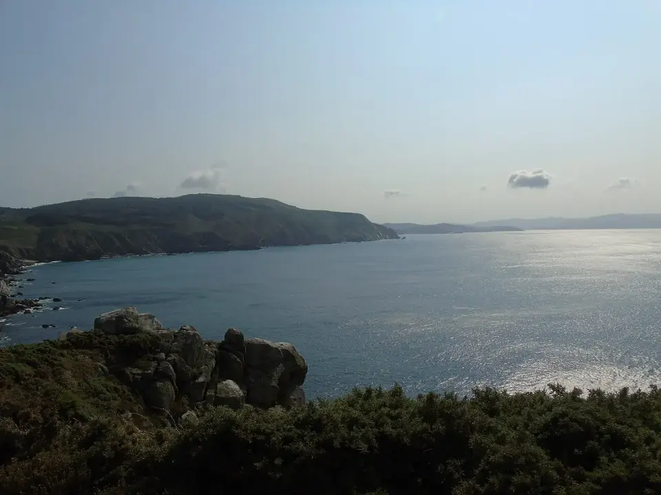 Costa de la Estaca de Bares con rocas en primer plano y el mar Cantábrico brillando al atardecer