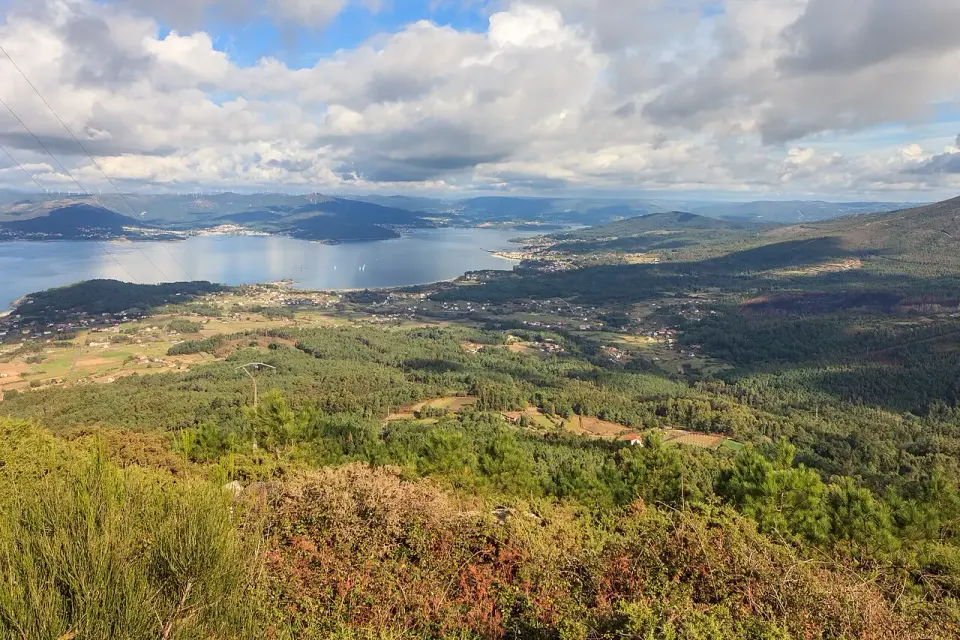 Vista desde lo alto de la ría de Muros e Noia, con la costa verde, pueblos dispersos y montes al fondo
