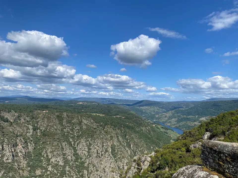 Vista del cañón del Sil desde un mirador de la Ribeira Sacra, con laderas de roca y bosque y el río al fondo bajo un cielo con nubes