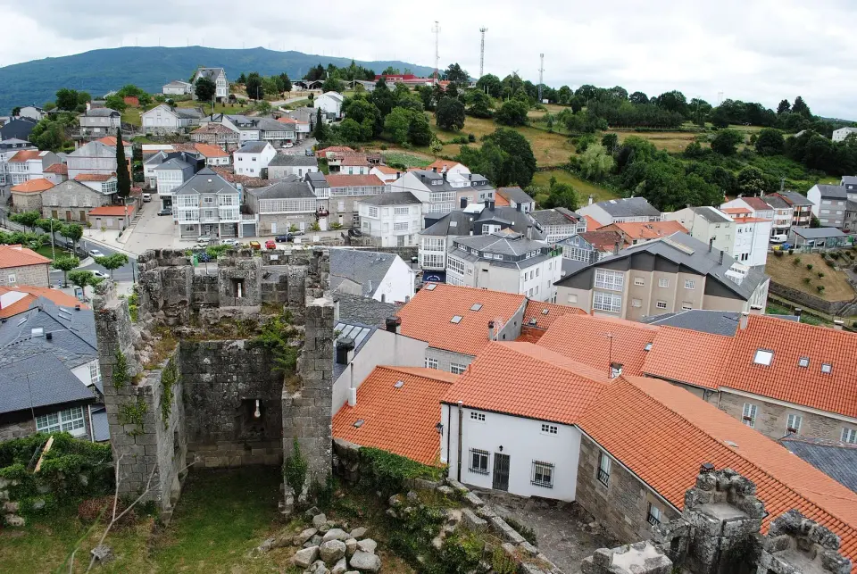 Castro Caldelas visto desde su castillo, con los restos de una torre en primer plano y los tejados del pueblo detrás