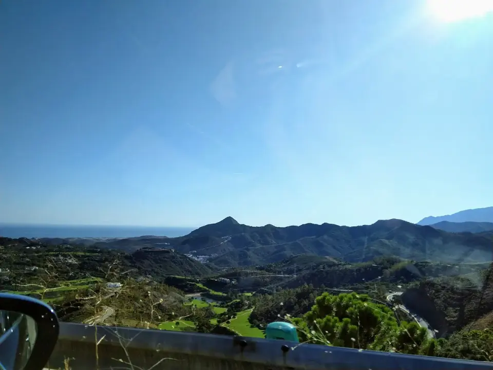 Vista desde la A-397 hacia la Costa del Sol, con sierras verdes y el mar Mediterráneo al fondo