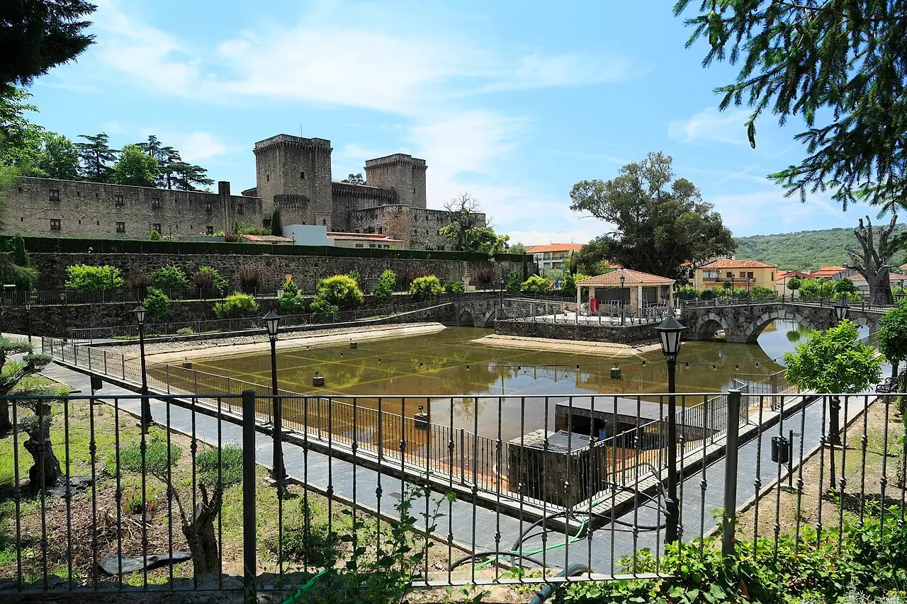Castillo de los Condes de Oropesa en Jarandilla de la Vera, hoy parador, visto desde el parque de la Aliseda con un estanque y jardines