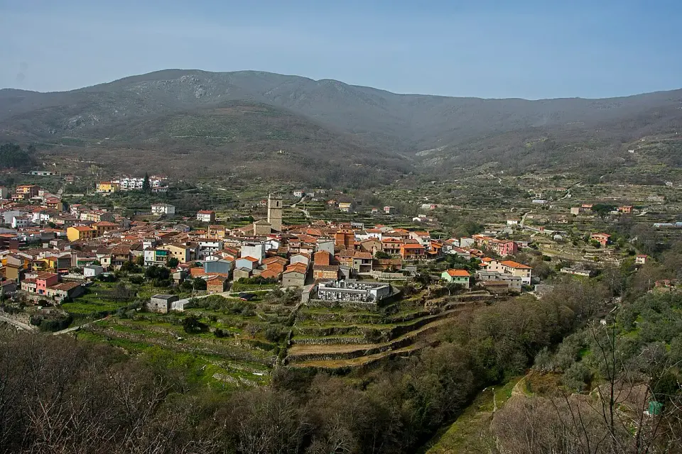 Vista de Garganta la Olla con sus tejados entre huertos en terrazas y la sierra de Tormantos al fondo