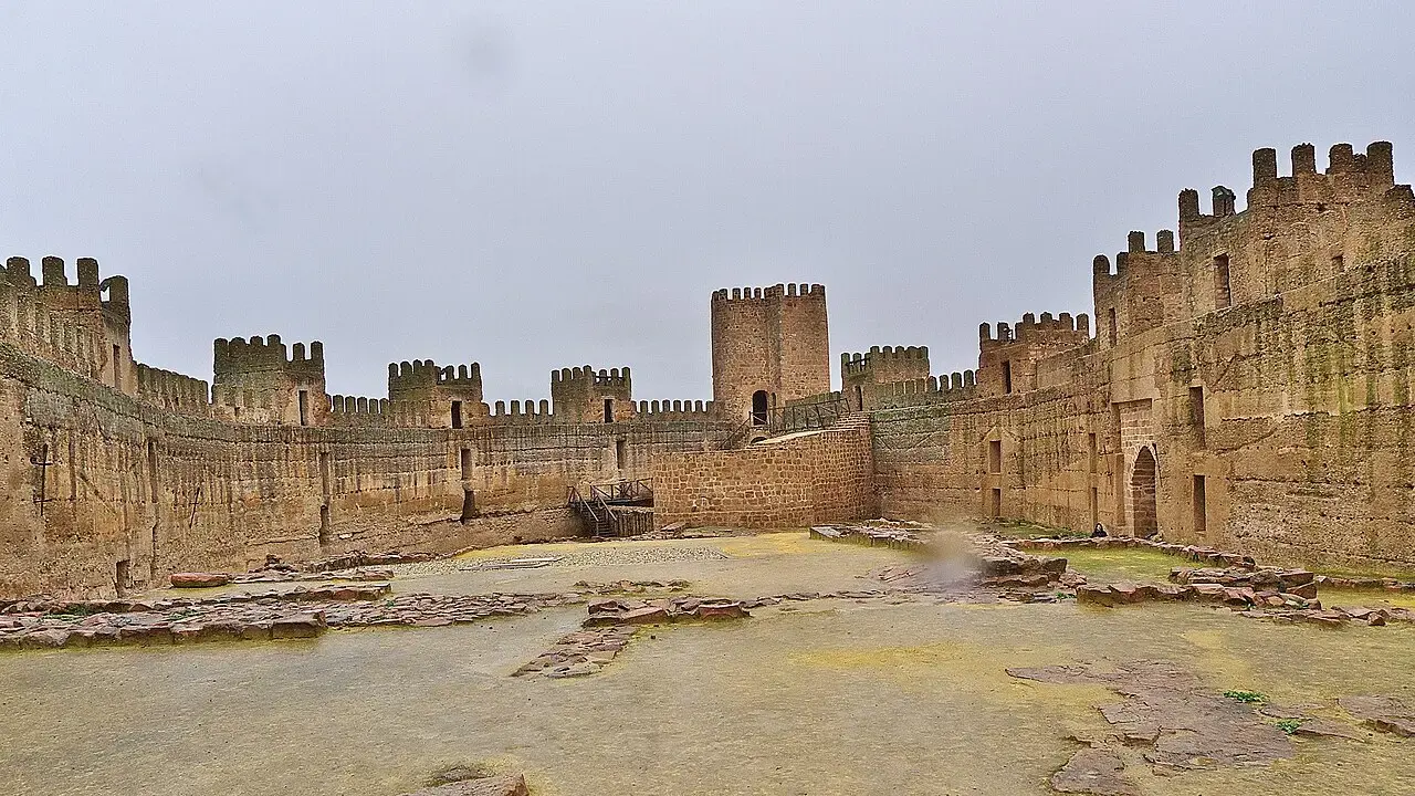 Patio de armas del castillo de Burgalimar en Baños de la Encina, rodeado de murallas almenadas con torres cuadradas